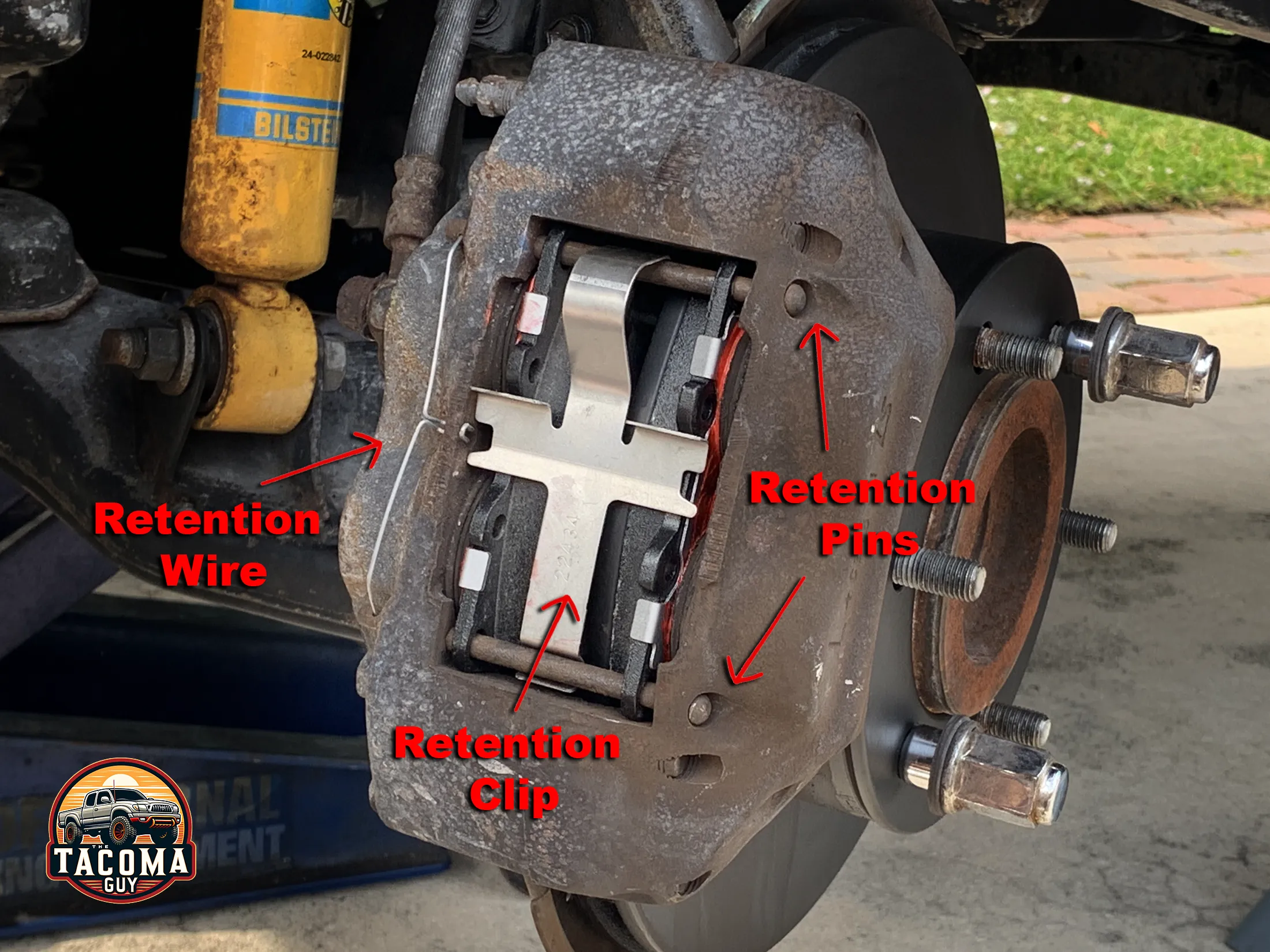 Close-up of a front caliper of a Gen 1 Toyota Tacoma showing the brake pads and rotor. 