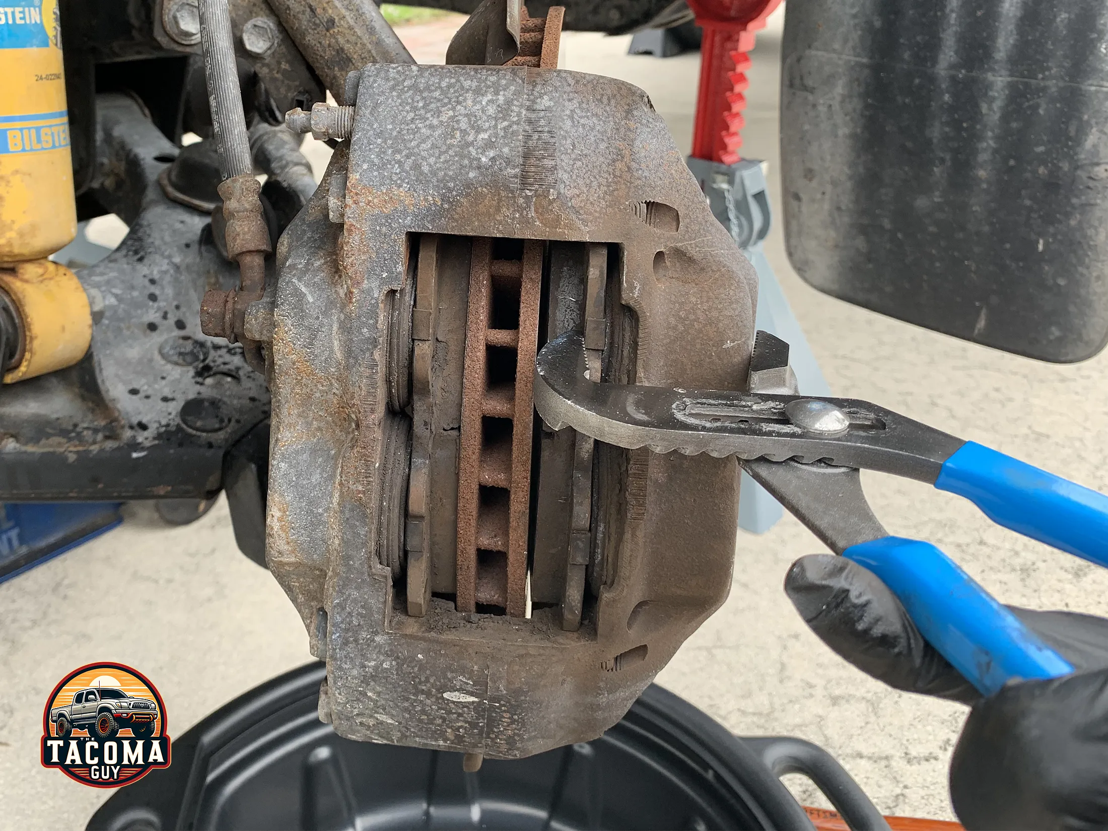 Using channel locks to depress brake pads against caliper pistons on a gen 1 toyota tacoma