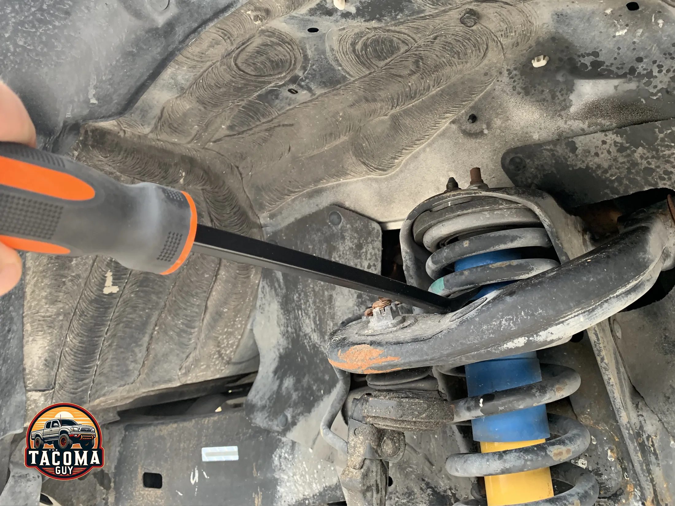 Using a 16" pry bar to push down on the upper control arm of a gen 1 toyota tacoma to relieve pressure on the shock absorber in order to remove it. 